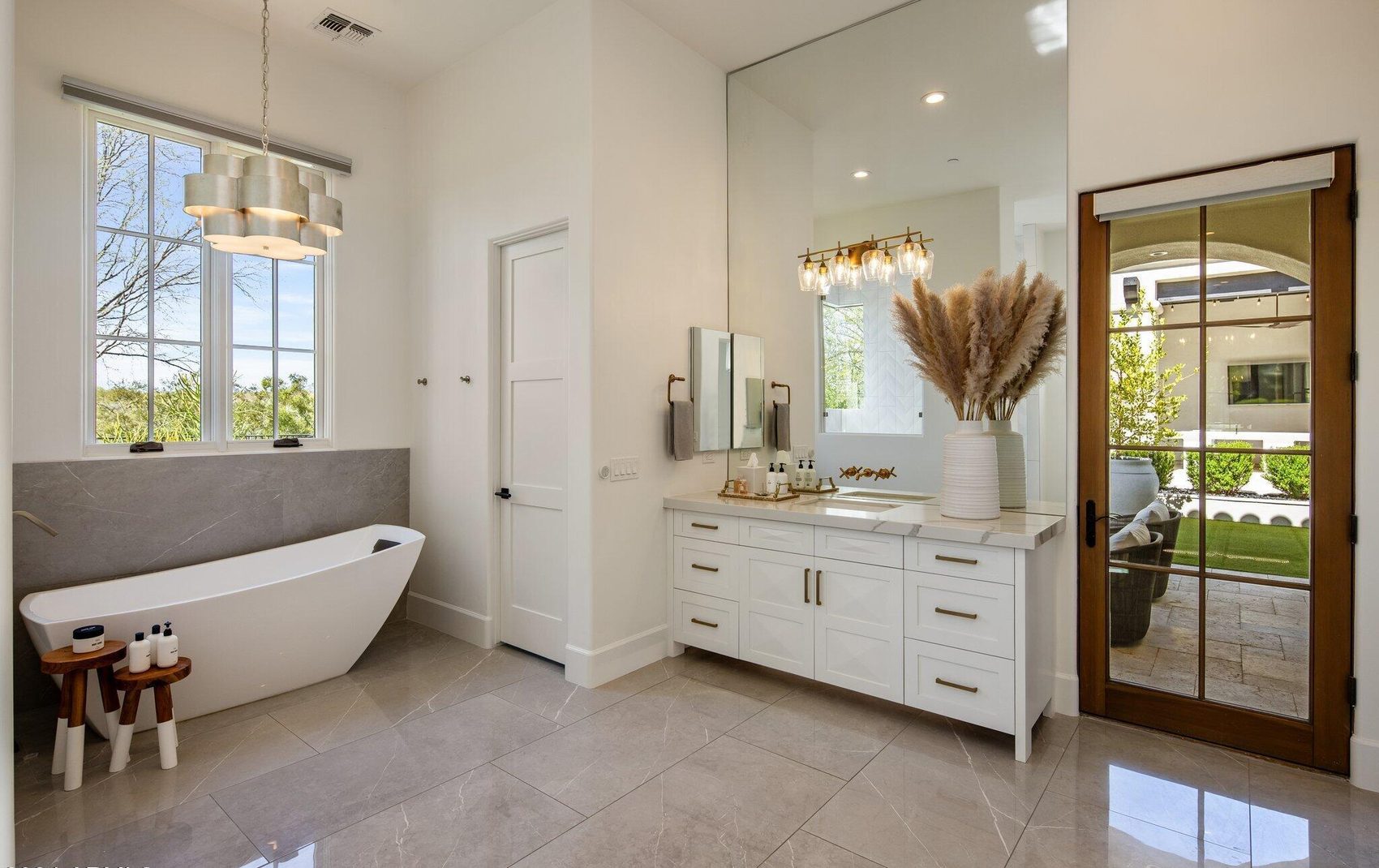 The primary bath after — freestanding soaking tub, double vanity, white and gold