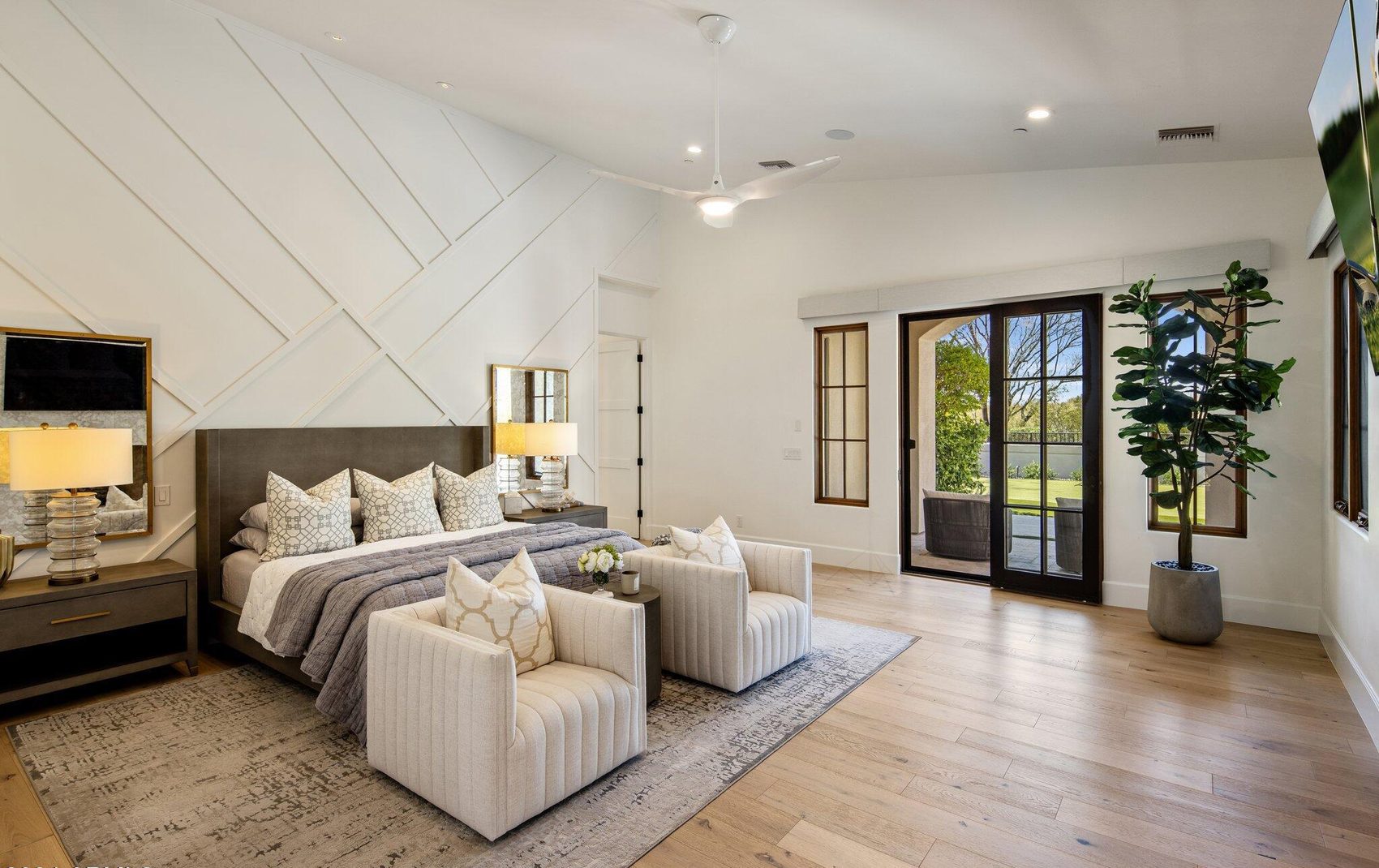 Primary suite with white oak floors, a furnished sitting area and mountain views