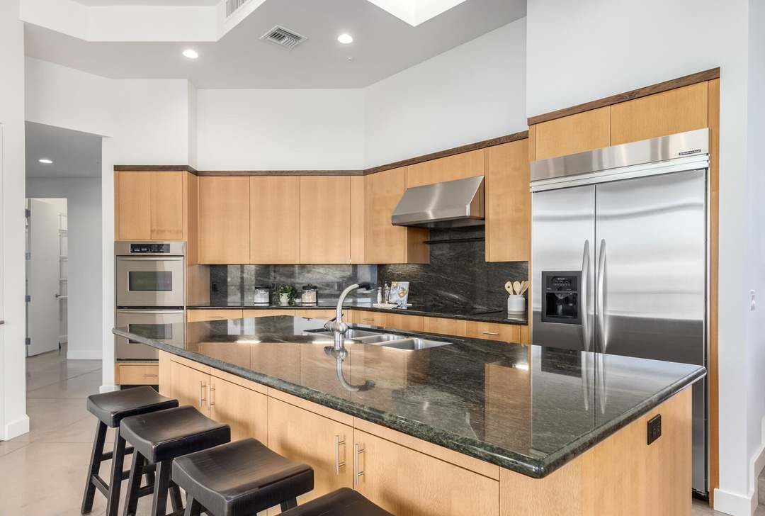 The kitchen as purchased — maple cabinetry, dark granite and a raised bar